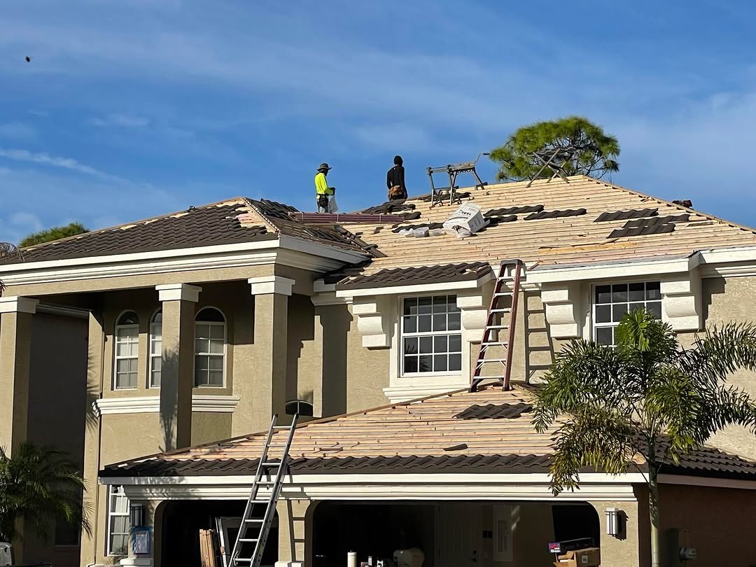 Two roofers working on tile roof with ladders
